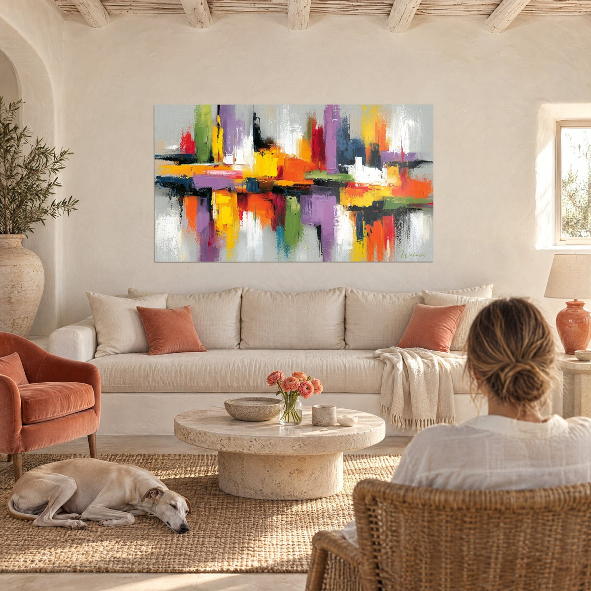 Πίνακας αφηρημένης σιλουέτας πόλης με πινελιές σπάτουλας σε πορτοκαλί, μωβ και κίτρινο, μια γυναίκα από πλάτης και ένα λαγωνικό, πάνω από έναν καναπέ σε φωτεινό σαλόνι