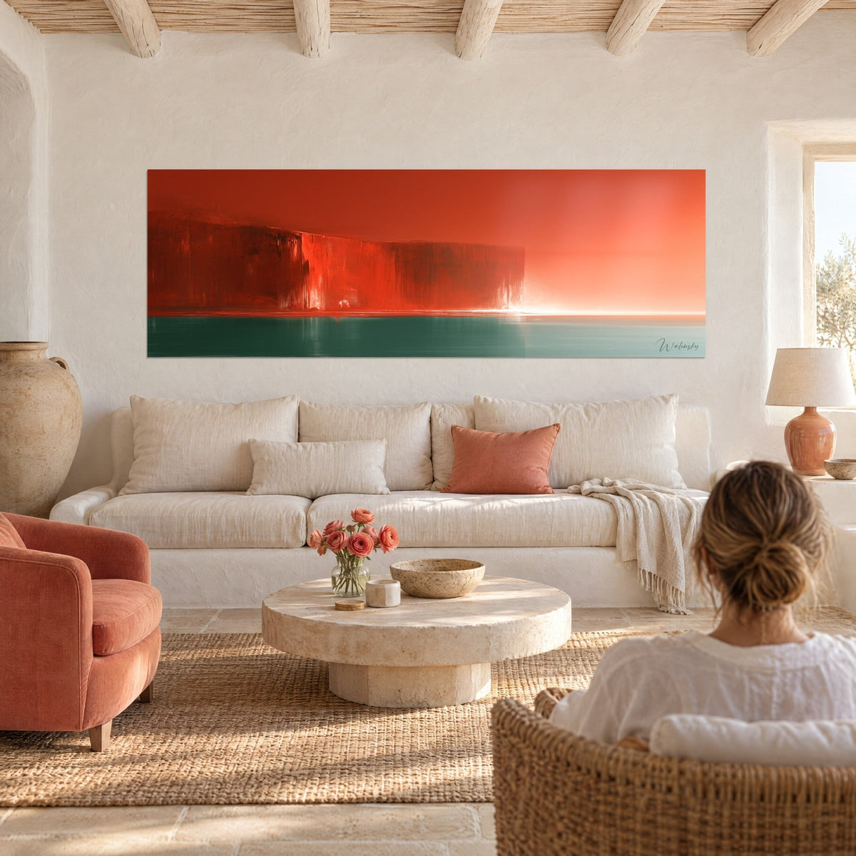 Gemälde einer scharlachroten Klippe vor einem tannengrünen Meer, dunstig orangefarbener Himmel, Frau von hinten über einem Sofa in einem hellen Wohnzimmer