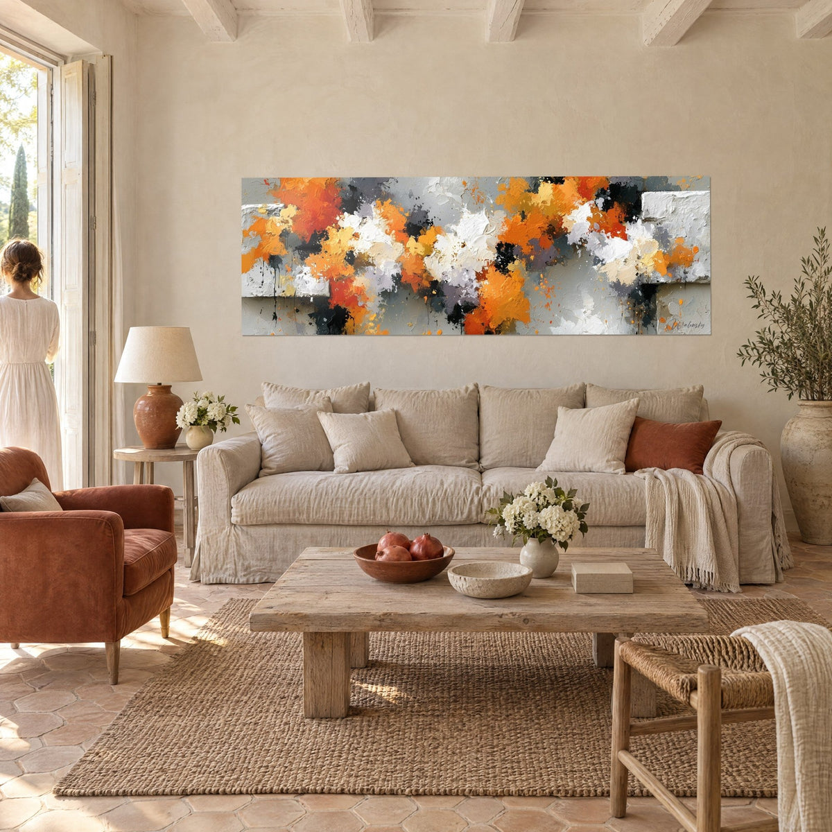 Wall art with bright orange splashes and charcoal grey, thick white paint textures, two people seen from behind, above a sofa in a bright living room