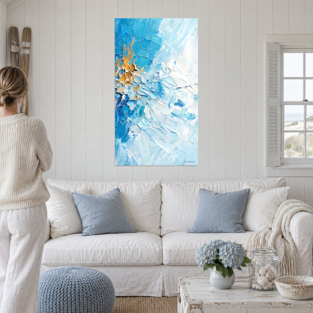 Tableau coups de spatule bleu turquoise et blanc, éclat doré à gauche, au-dessus d'un canapé dans un salon lumineux