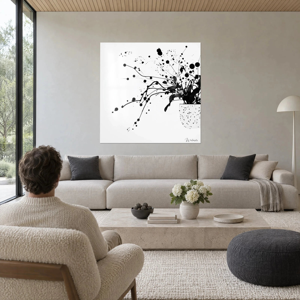 Schilderij zwart inktboeket in een bundel, spatten op puur witte achtergrond, boven een bank in een lichte woonkamer