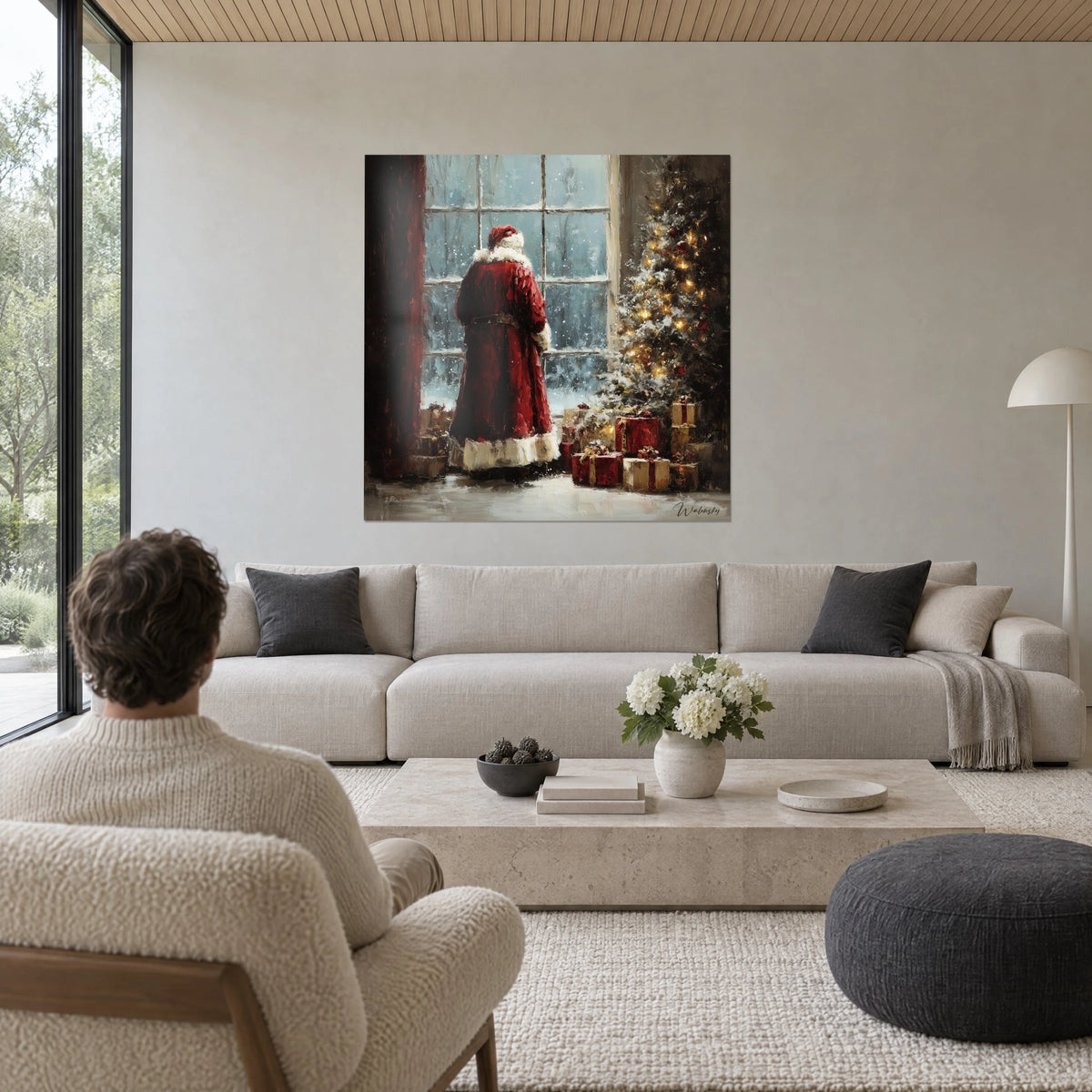 Cuadro Papá Noel de espaldas con abrigo rojo frente a una ventana nevada, abeto dorado, encima de un sofá en un salón luminoso