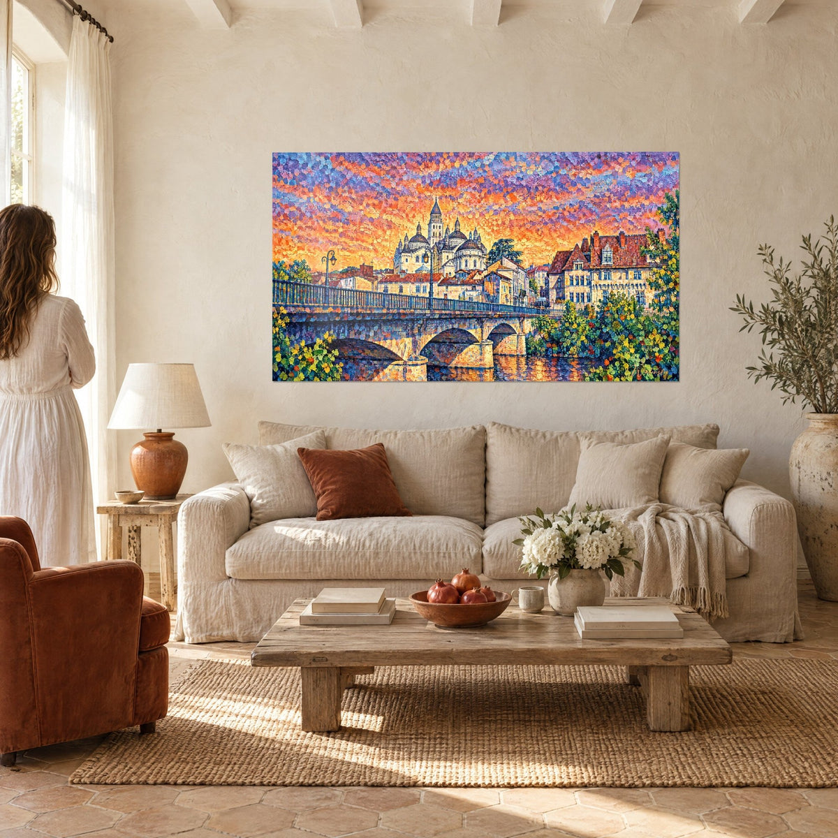 Tableau cathédrale à coupoles ocre sous un ciel orange et violet, pont de pierre, femme de dos, au-dessus d'un canapé dans un salon lumineux