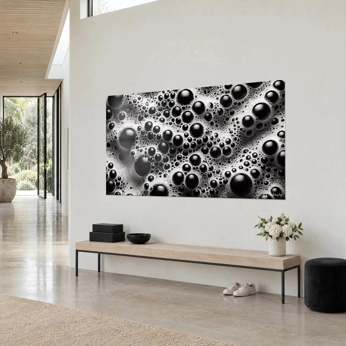 Wall art with glossy black bubbles of all sizes on ivory foam, three-quarter view, above a wooden bench in a bright entryway