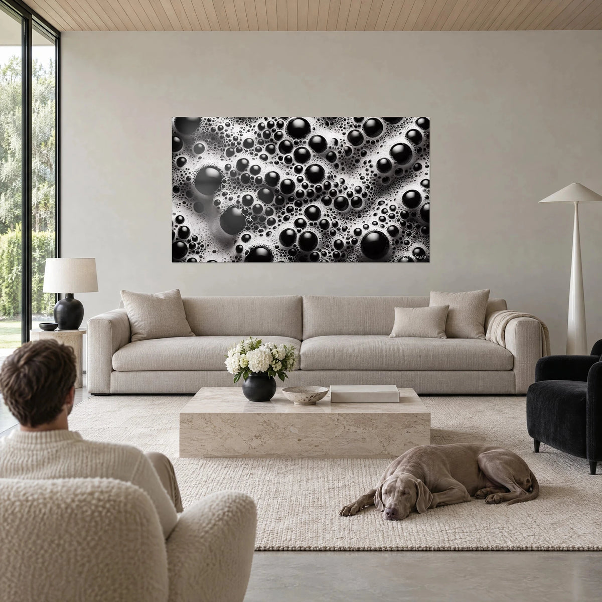 Wall art with monochrome foam dotted with glossy ebony beads on a white background, a Weimaraner lying down above a sofa in a bright living room