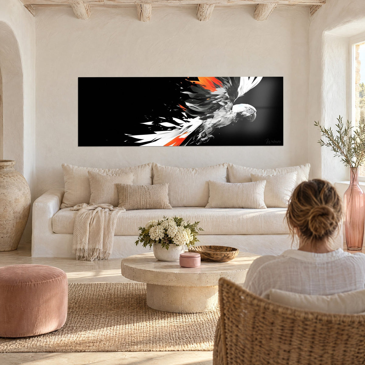 Gemälde Ara im Flug, weiß, mit grauen Federn und leuchtend orangefarbenen Akzenten auf schwarzem Hintergrund, über einem Sofa in einem hellen Wohnzimmer