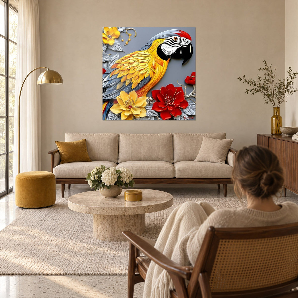 Cuadro Guacamayo amarillo con plumaje esculpido, flores rojas y grises, mujer de espaldas, sobre un sofá en un salón luminoso