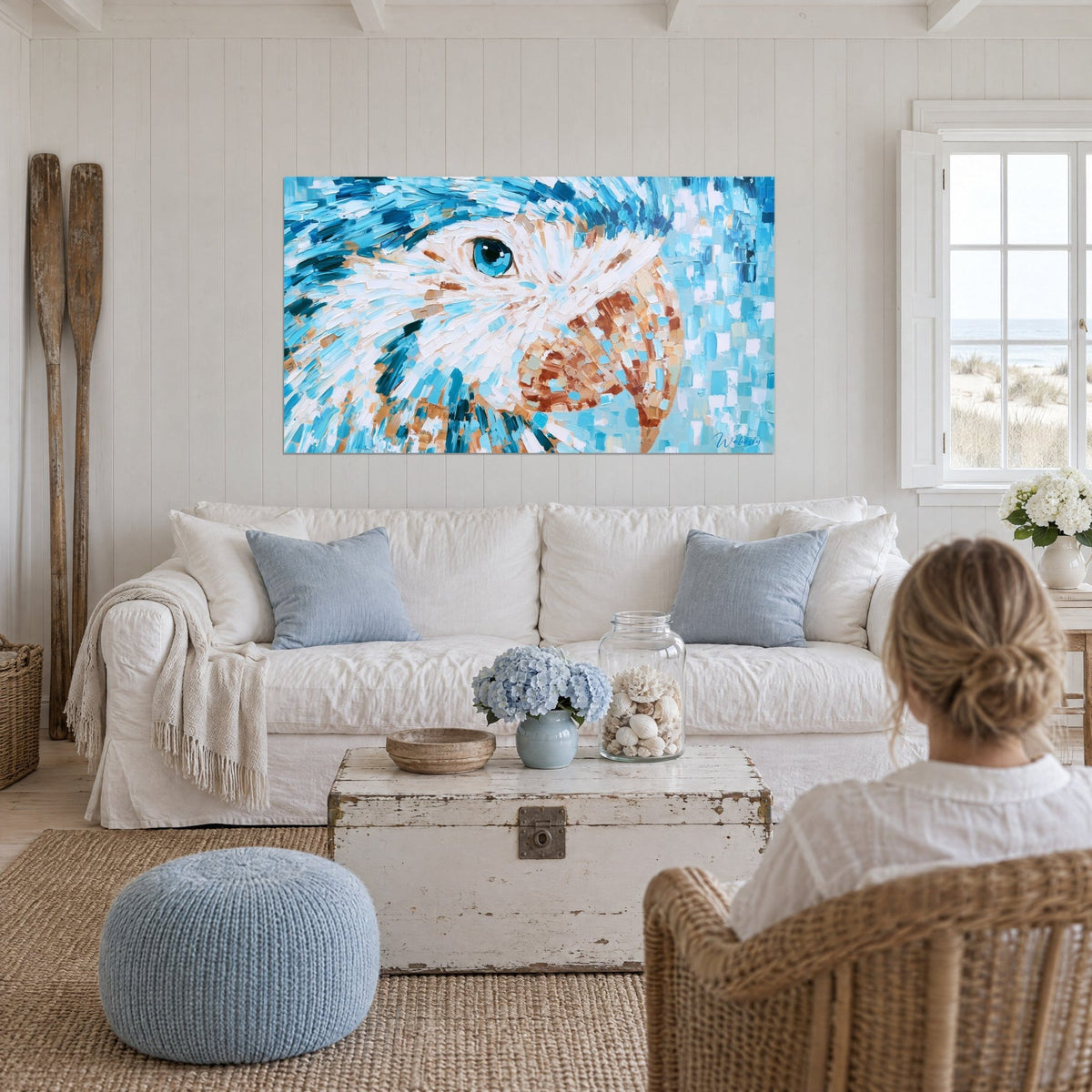 Gemälde Papagei mit türkisfarbenem und weißem Gefieder, leuchtend blaues Auge und kupferfarbener Schnabel, über einem Sofa in einem hellen Wohnzimmer
