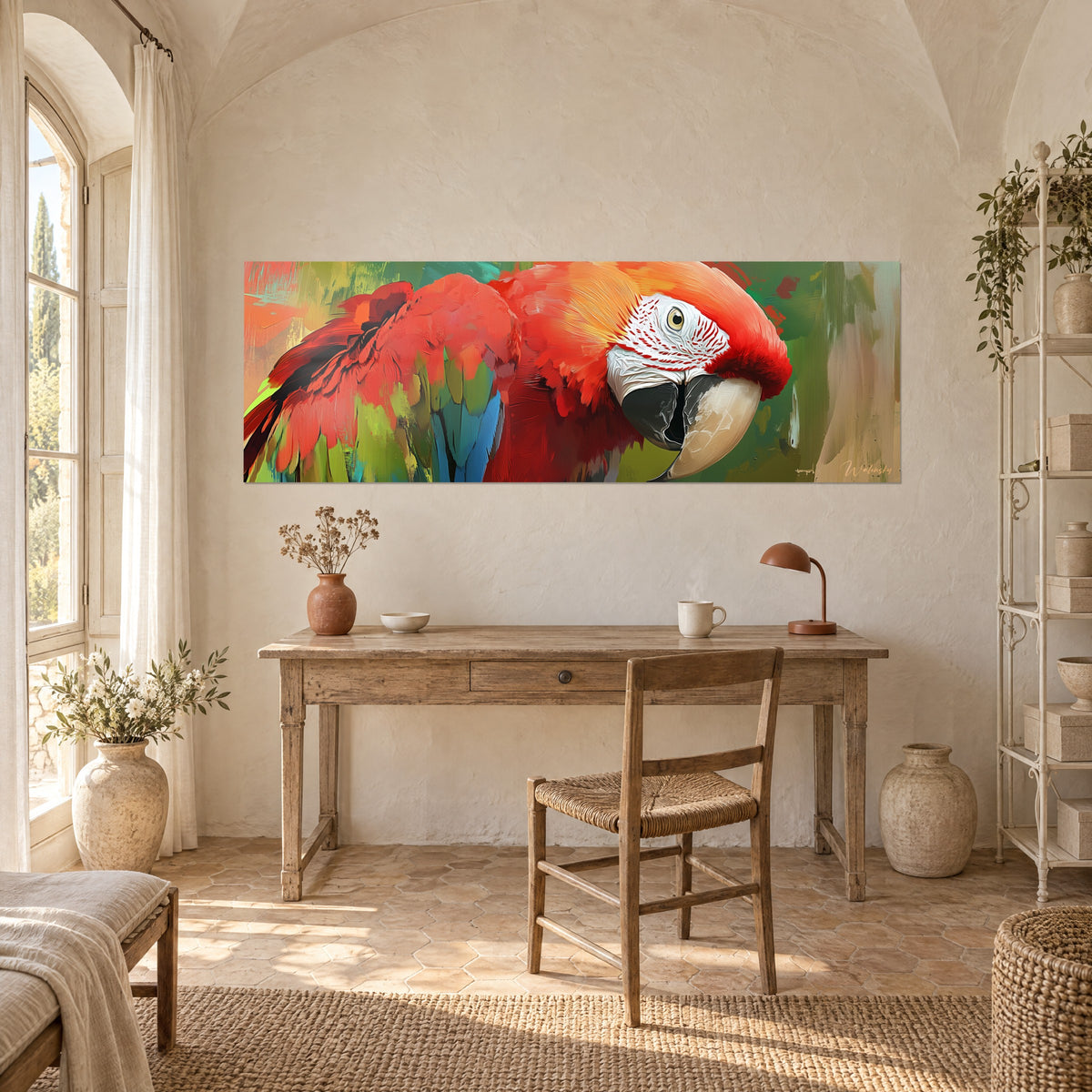 Cuadro loro de trazos vivos rojos y amarillos, fondo verde salvia, sobre un escritorio de madera clara