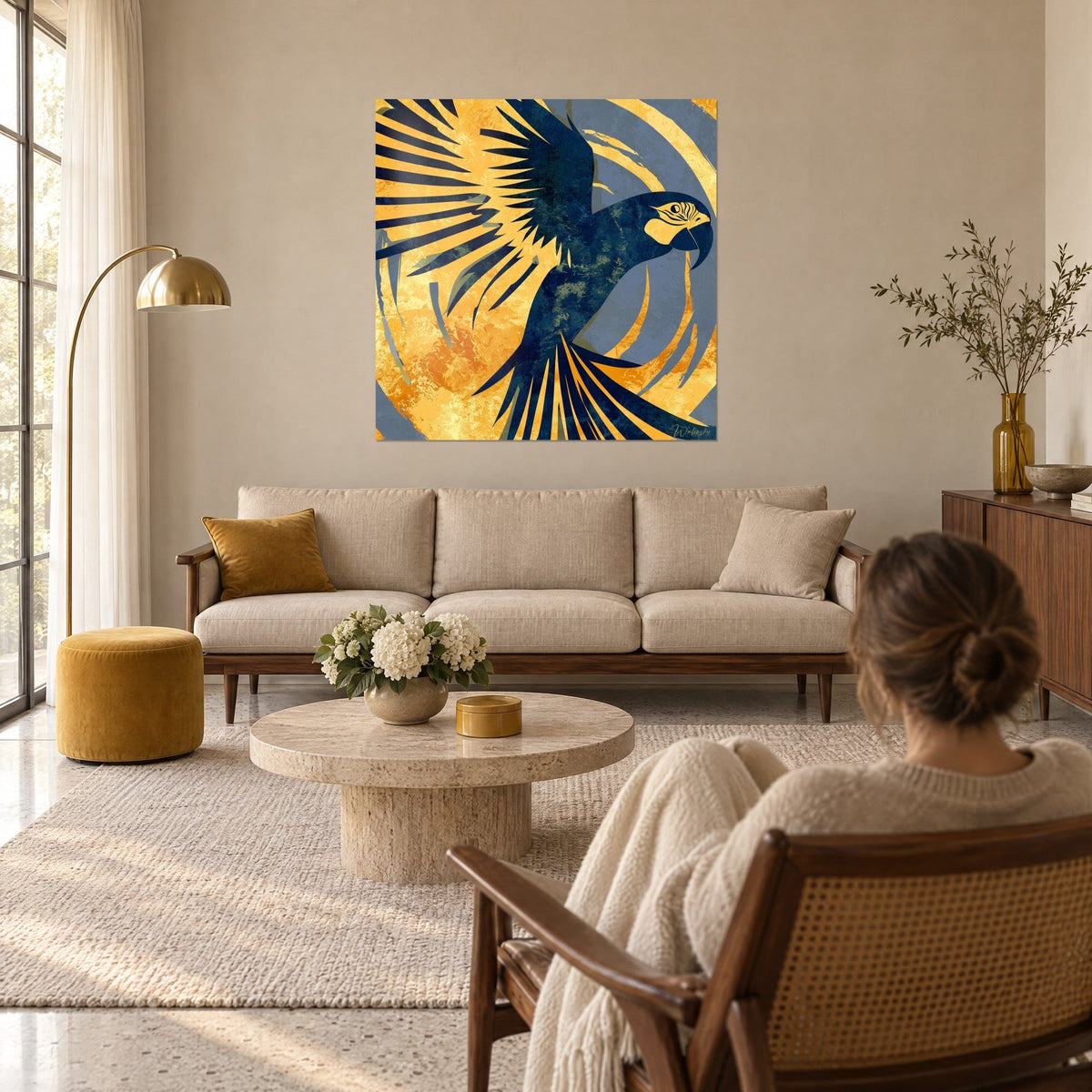 Quadro ara blu navy con ali spalancate su sfondo giallo zafferano, donna di spalle, sopra un divano in un soggiorno luminoso