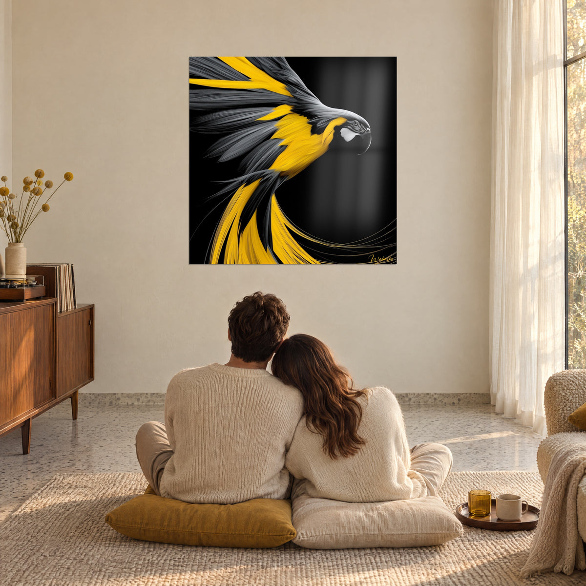 Wall art of a golden parrot with grey wings fanned out on a black background, watched by an embracing couple on mustard cushions in a living room