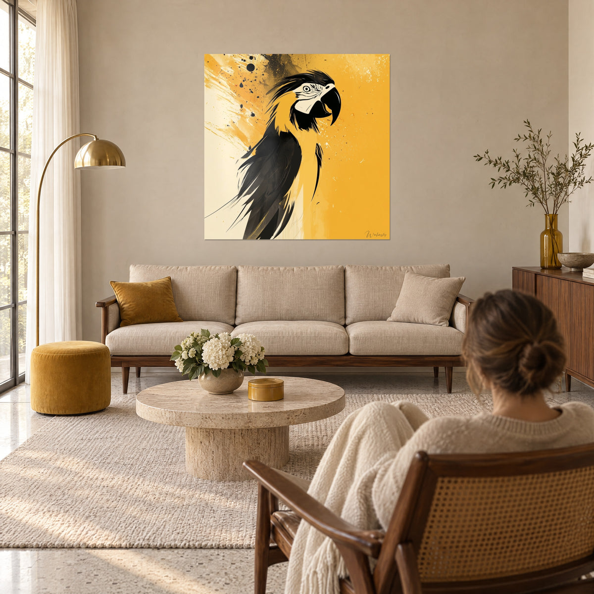 Schilderij Gele en zwarte ara met gebogen snavel, pluimen in de war en inktspatten, boven een bank in een lichte woonkamer. Walensky