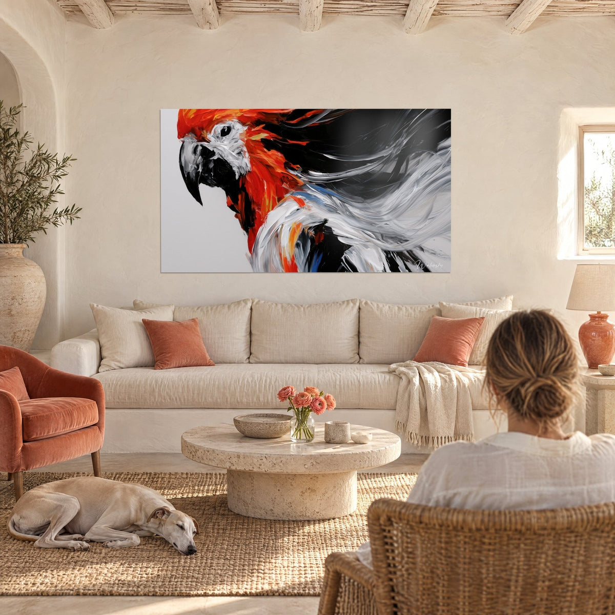 Gemälde Scharlachroter Papagei mit schwarzem Schnabel und verwehten weißen Federsträhnen, eine Frau von hinten über einem Sofa in einem hellen Wohnzimmer