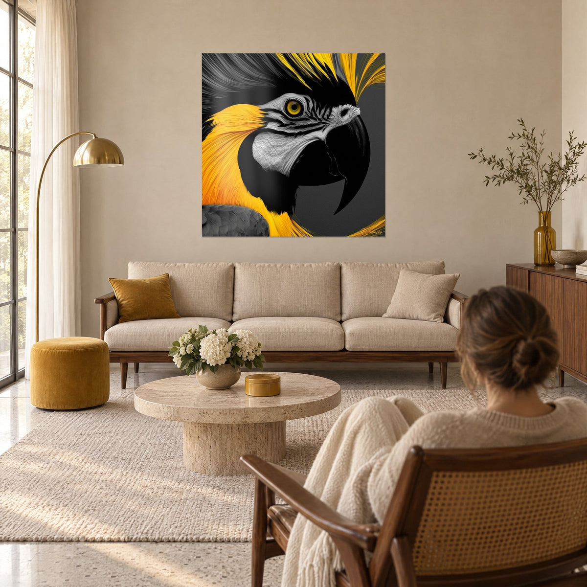 Quadro Ara giallo e nero dallo sguardo penetrante, piume dorate su fondo grigio, donna di spalle, sopra un divano in un soggiorno luminoso