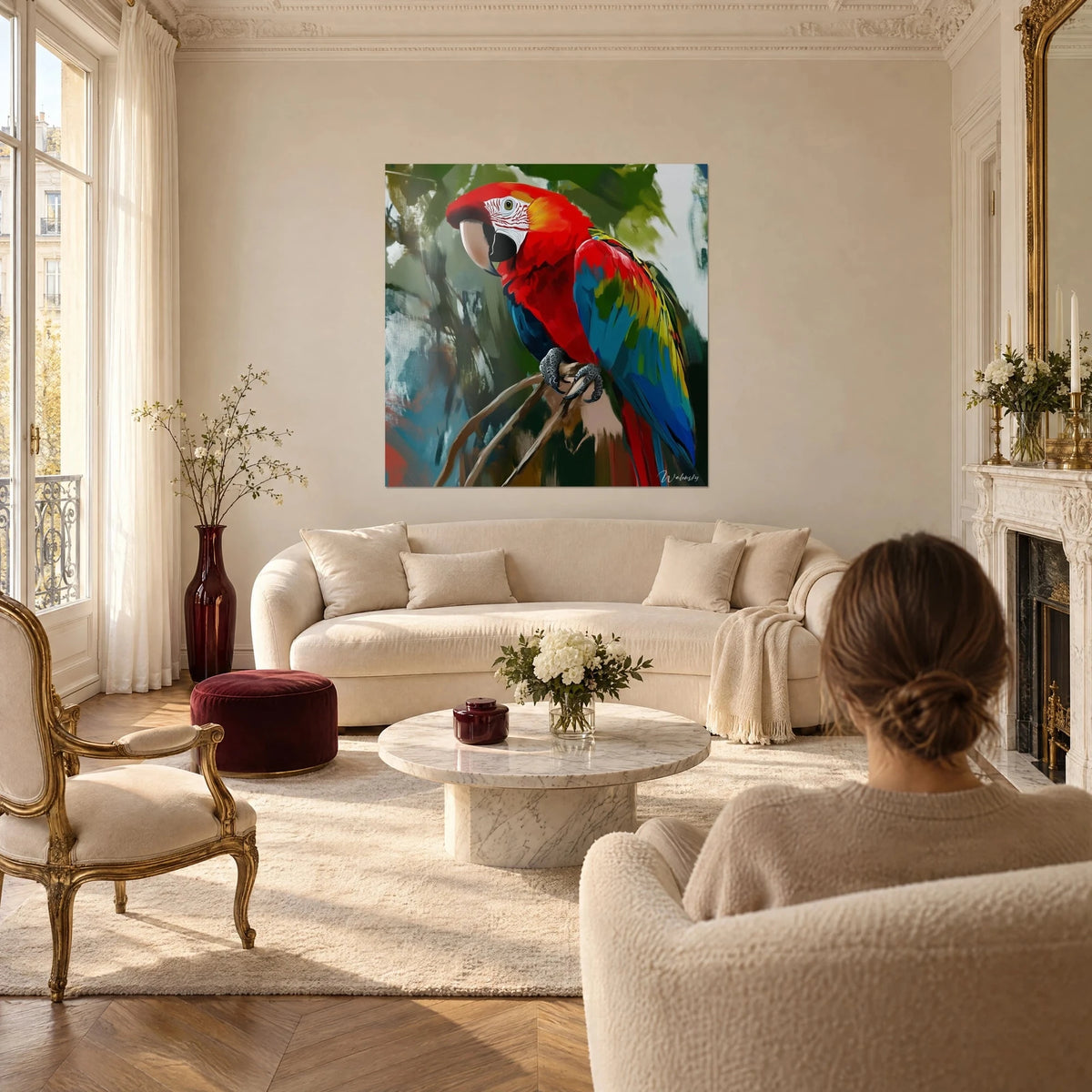 Gemälde eines auf einem Ast sitzenden Hellroten Aras, kobaltblaue und gelbe Flügel, ein Paar von hinten über einem Sofa in einem hellen Wohnzimmer