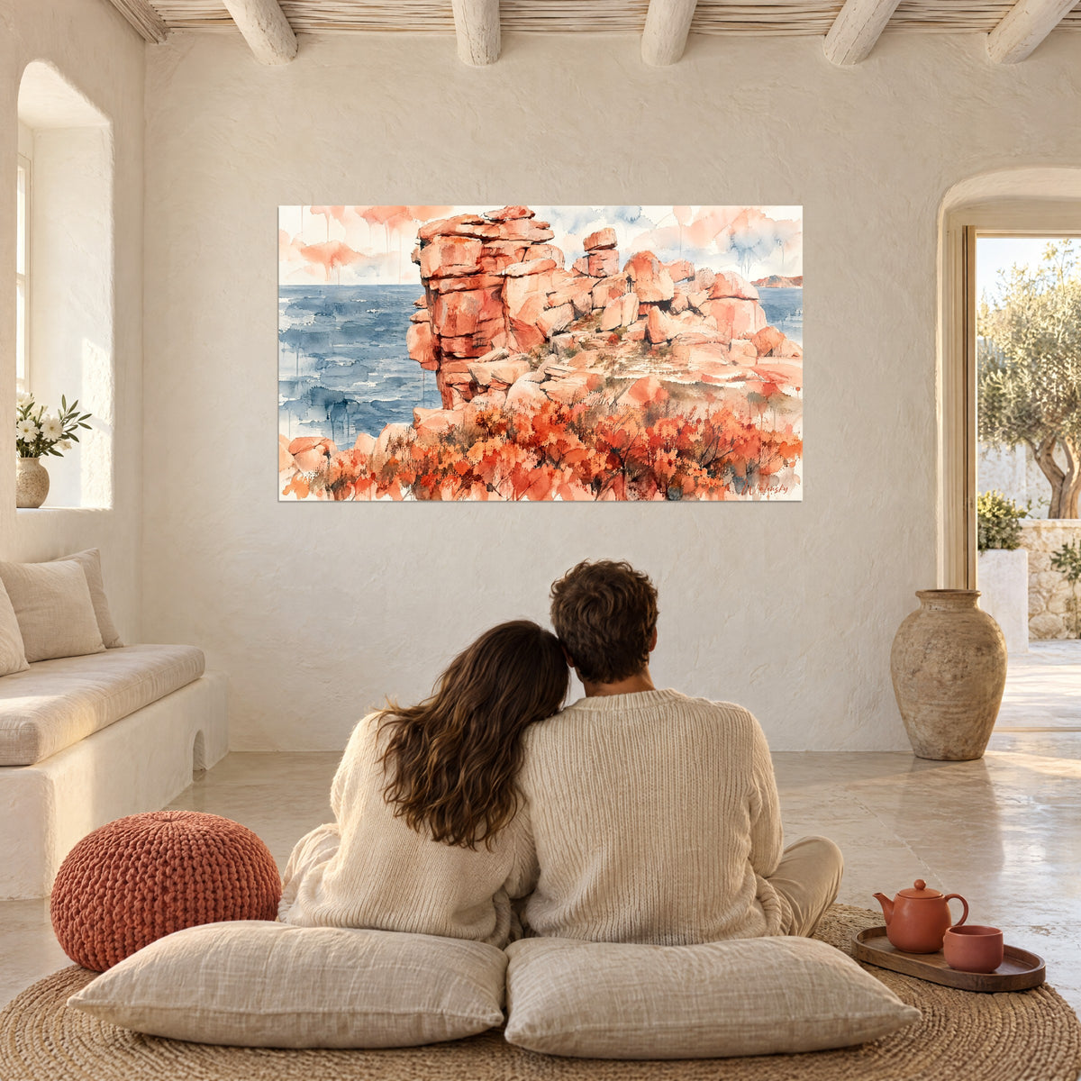 Quadro di granito rosa della Bretagna, mare blu e fiori rossi, coppia abbracciata di spalle su cuscini, pareti beige della casa