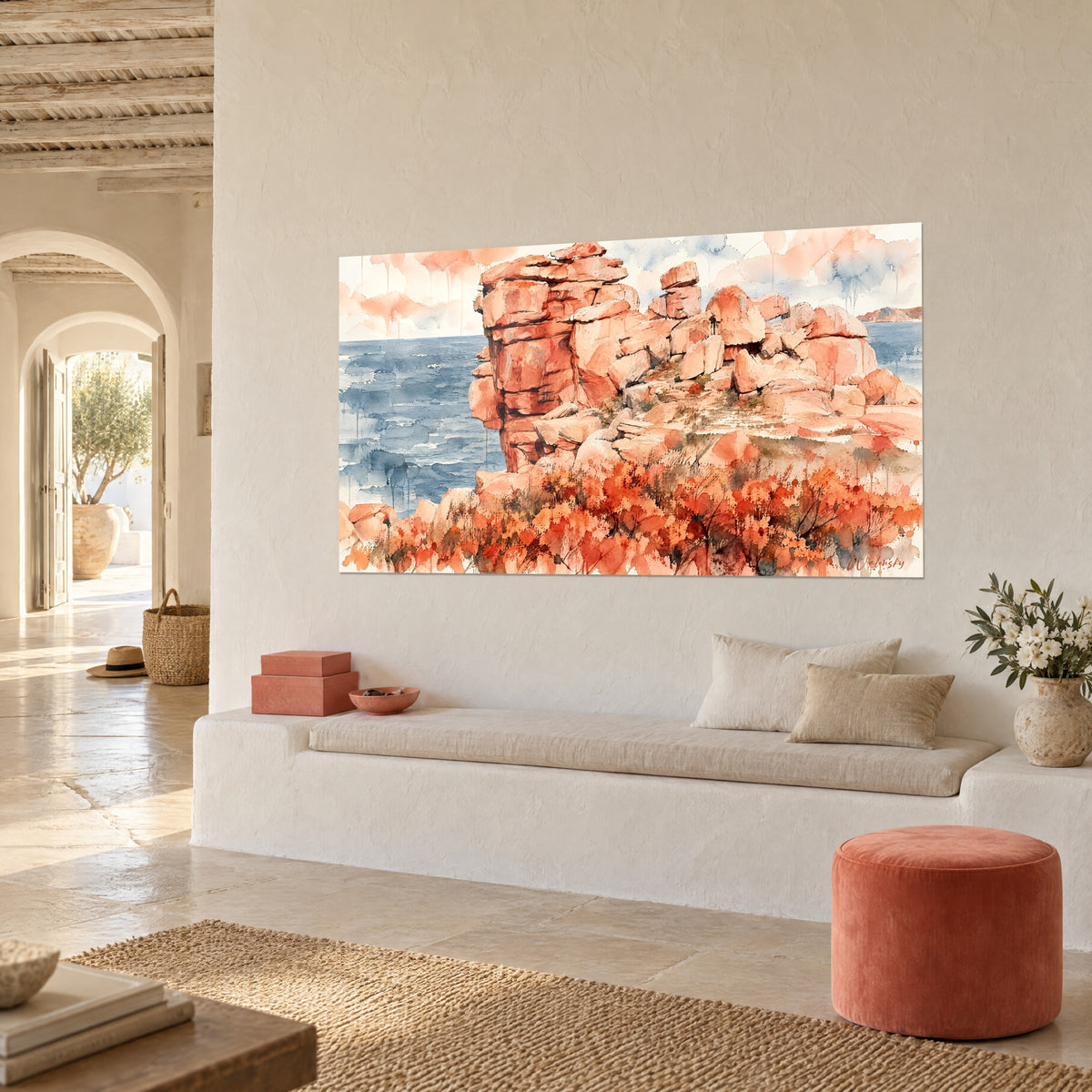 Quadro di una scogliera corallina con massi sovrapposti ed erica rossa, mare indaco, su una parete bianca, panca in pietra e pouf terracotta