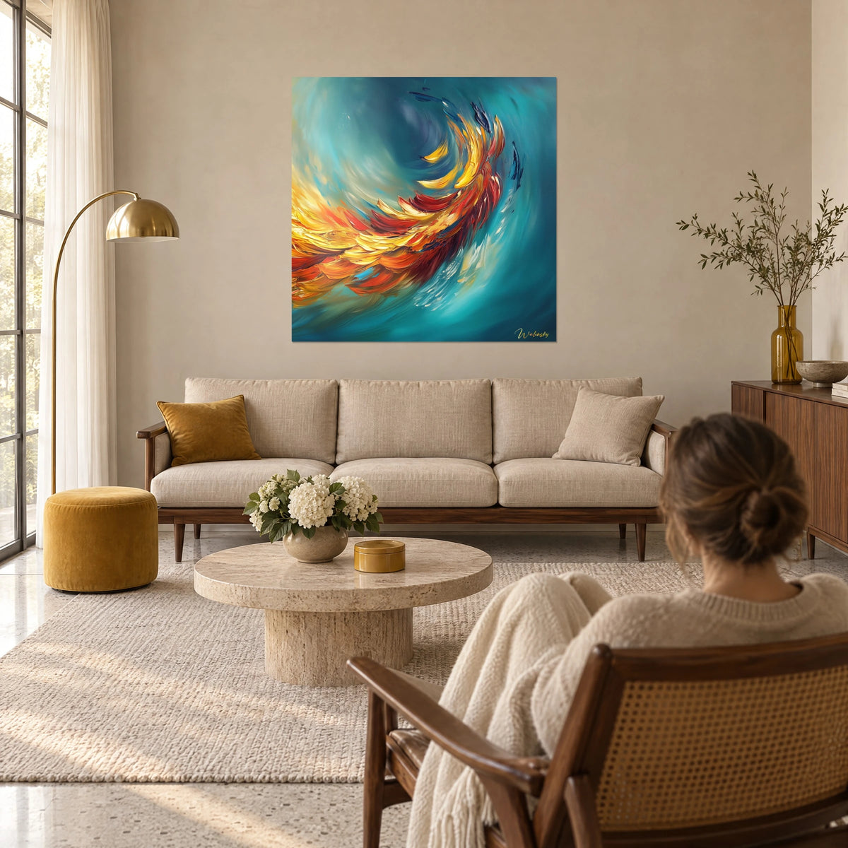 Schilderij van een vuurvogel met gele en rode veren op een turquoise achtergrond, van achteren bekeken door een vrouw, boven een bank in een lichte woonkamer