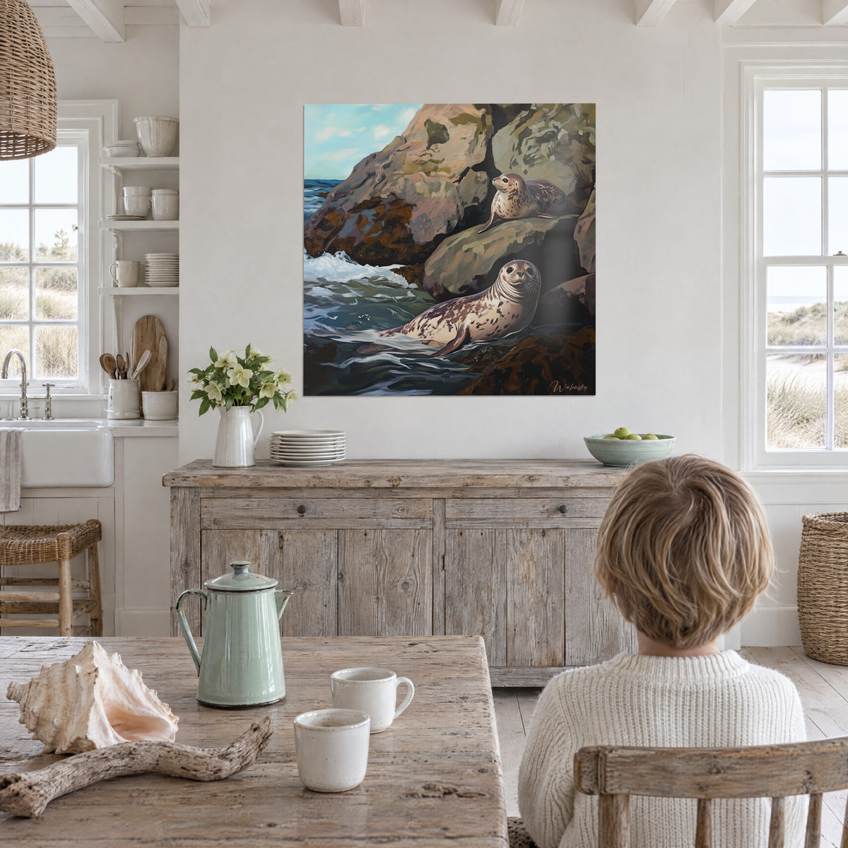 Schilderij jonge crèmekleurige zeehonden op een met mos begroeide rots, bruin zeewier en leigrijs schuim, kind van achteren in een keuken aan zee