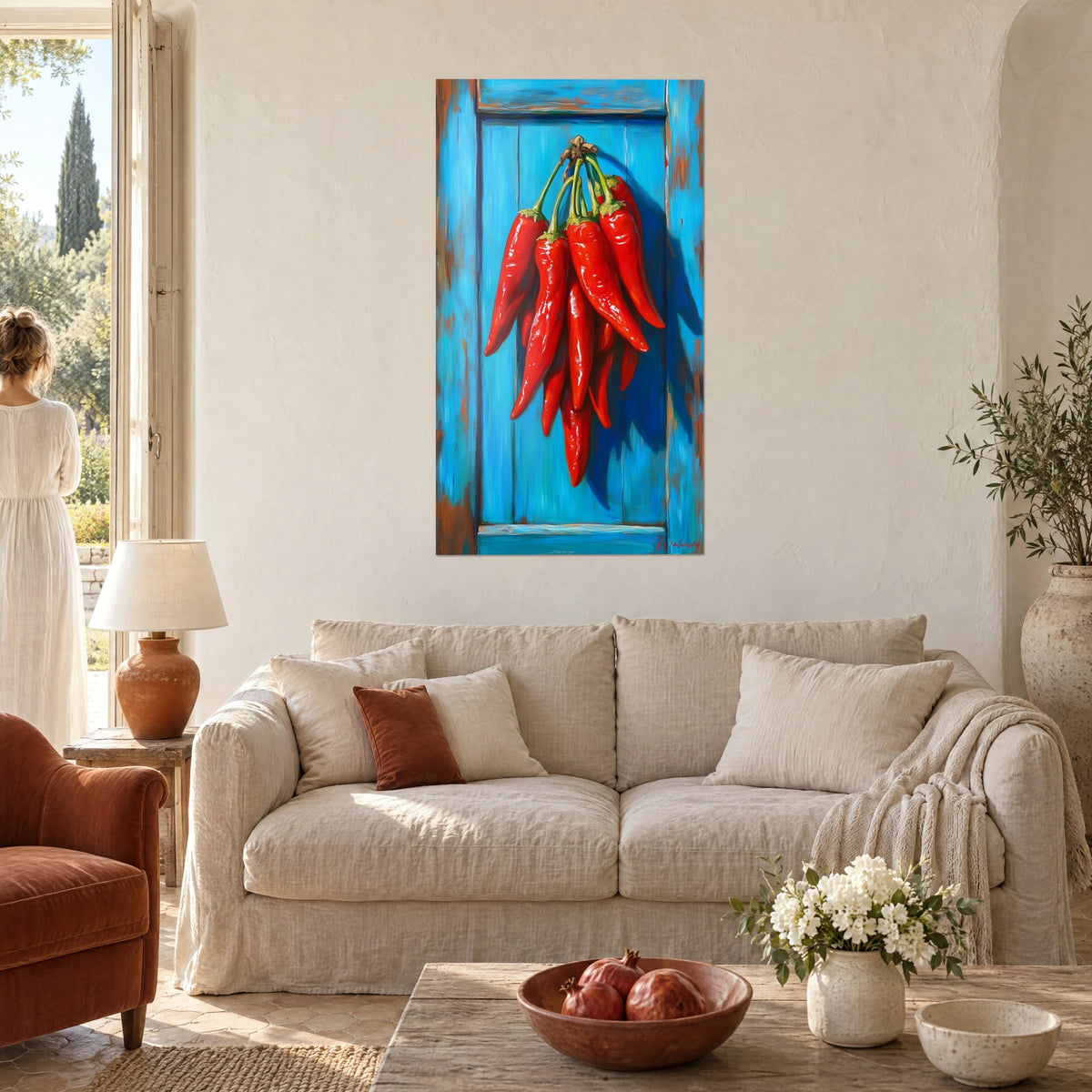 Tableau grappe de piments rouges luisants pendue à une porte turquoise écaillée, sur un mur chaux, au-dessus d'un canapé dans un salon lumineux