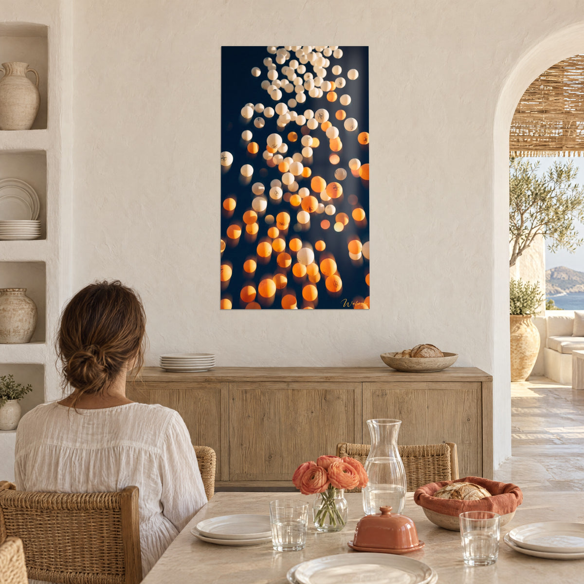 Cuadro con luz dorada sobre pelotas de ping-pong blancas y naranjas, comedor encalado, jarras y flores coral