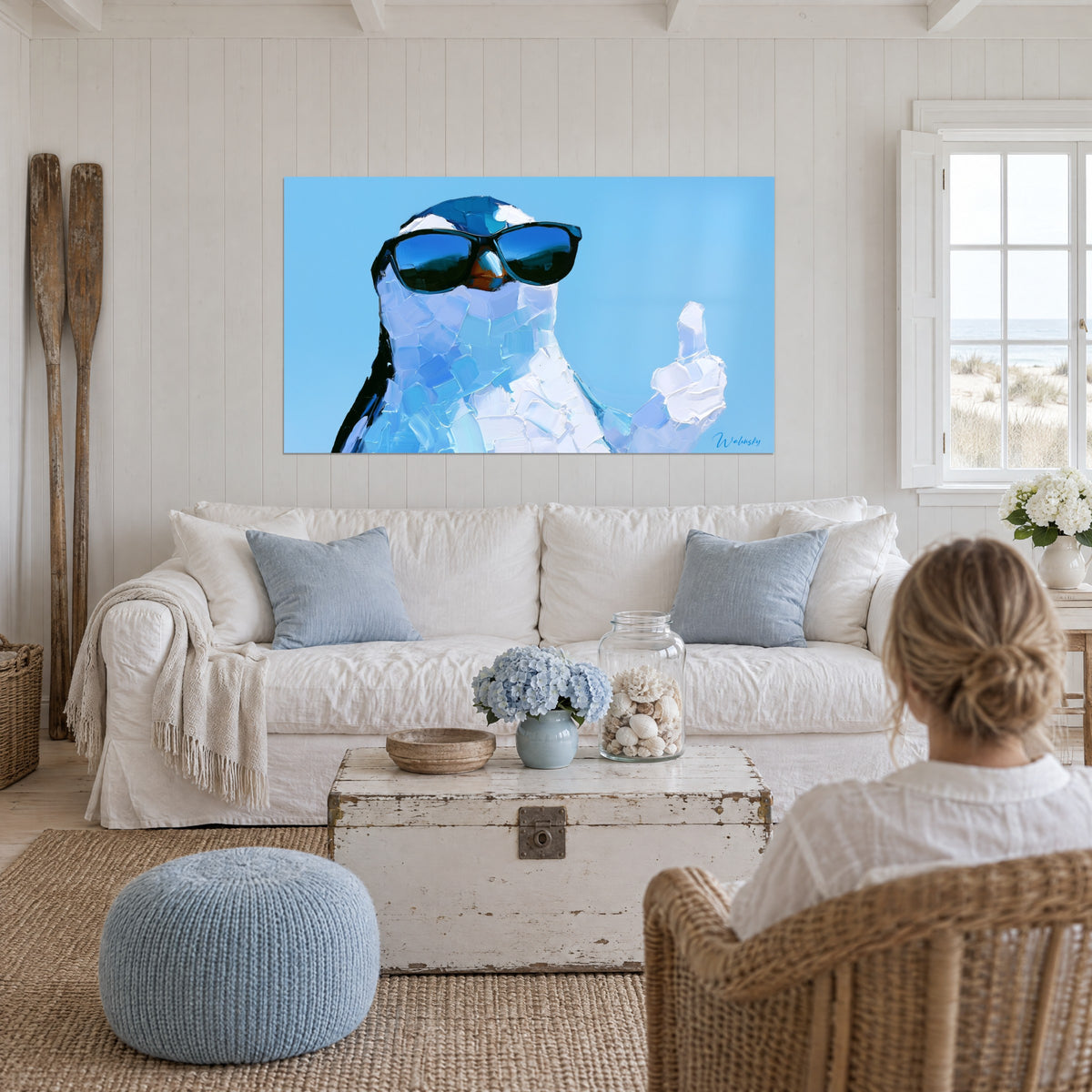 Gemälde Pinguin mit schwarzer Sonnenbrille, himmelblau und weiß, Daumen hoch, über einem Sofa in einem hellen Wohnzimmer