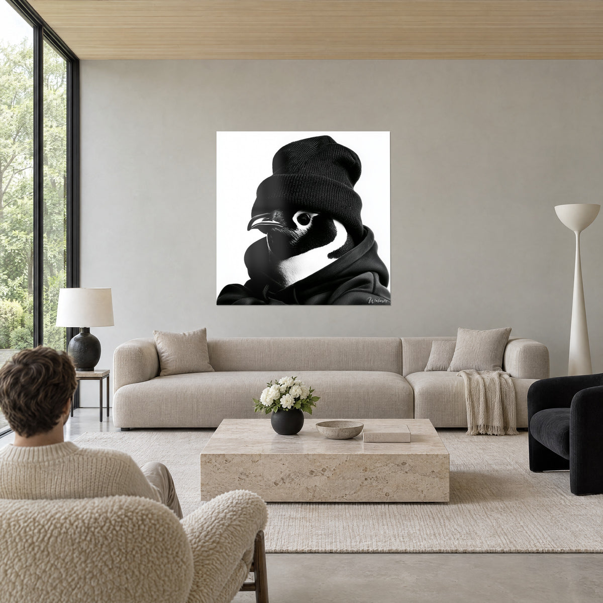Tableau pingouin au bonnet noir tricoté, bec lustré et capuche sombre sur fond blanc, au-dessus d'un canapé dans un salon lumineux