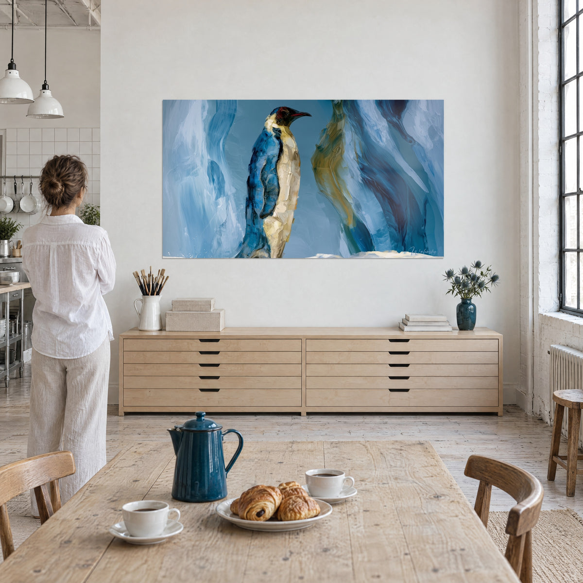 Schilderij keizerspinguïn van Antarctica in dik impasto, ultramarijnblauw en zacht goud, vrouw van achteren naast een tafel met croissants