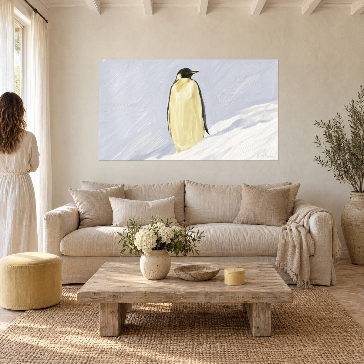 Wall art emperor penguin with pale yellow chest and black back, white snow slope, above a sofa in a bright living room
