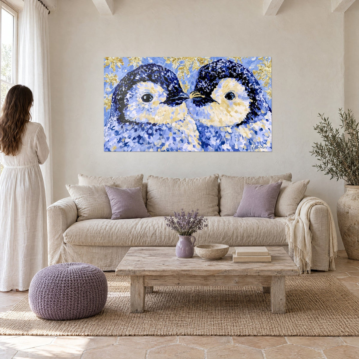 Cuadro dos pingüinos frente a frente, plumaje azul cobalto y vientre crema, picos juntos, sobre un sofá en un salón luminoso