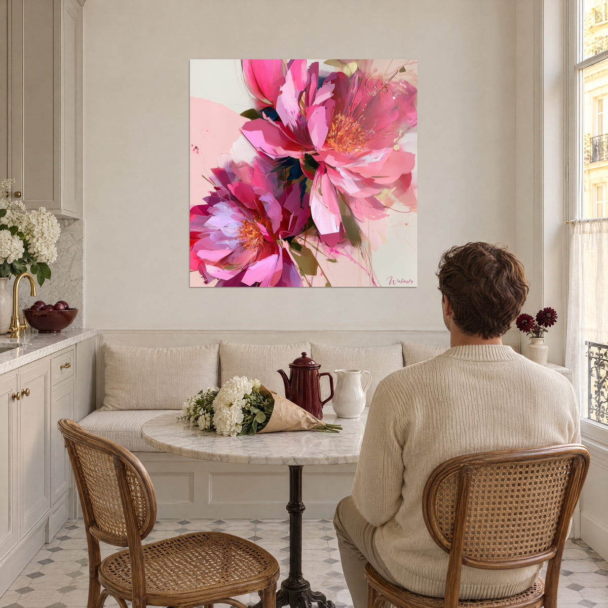 Schilderij grote snoeproze en magentakleurige bloemen met amberkleurige meeldraden, een man met zijn rug naar de kijker naast een ronde marmeren tafel, lichte keuken