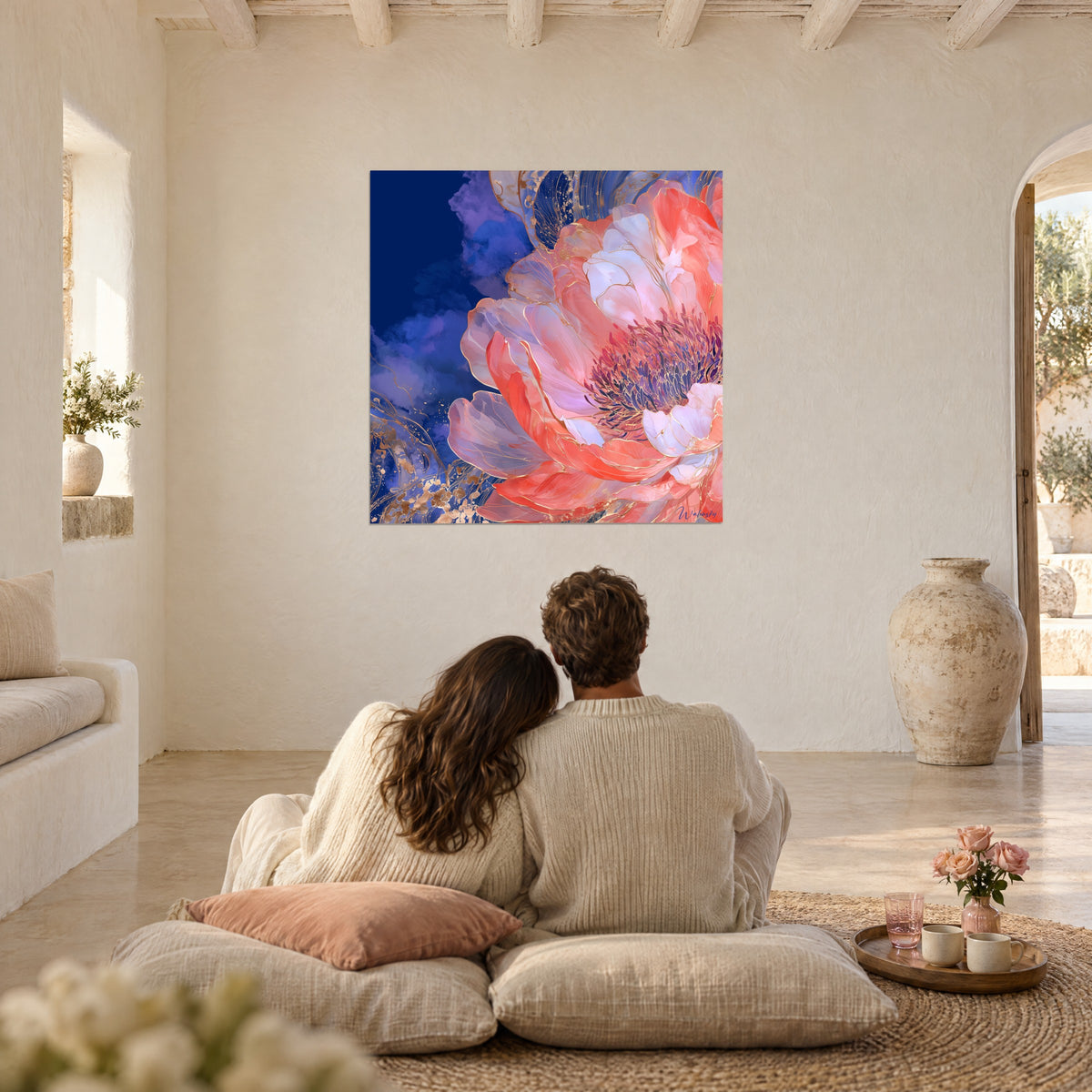 Wall art fully bloomed peony flower, salmon petals outlined in gold against an indigo sky, a couple seen from behind seated on cushions in the living room