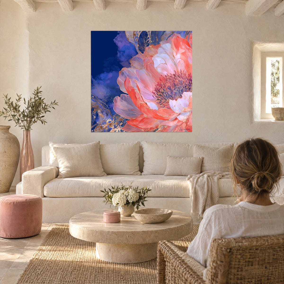 Wall art coral peony with gold-veined petals on midnight blue background, two people seen from behind, above a sofa in a bright living room