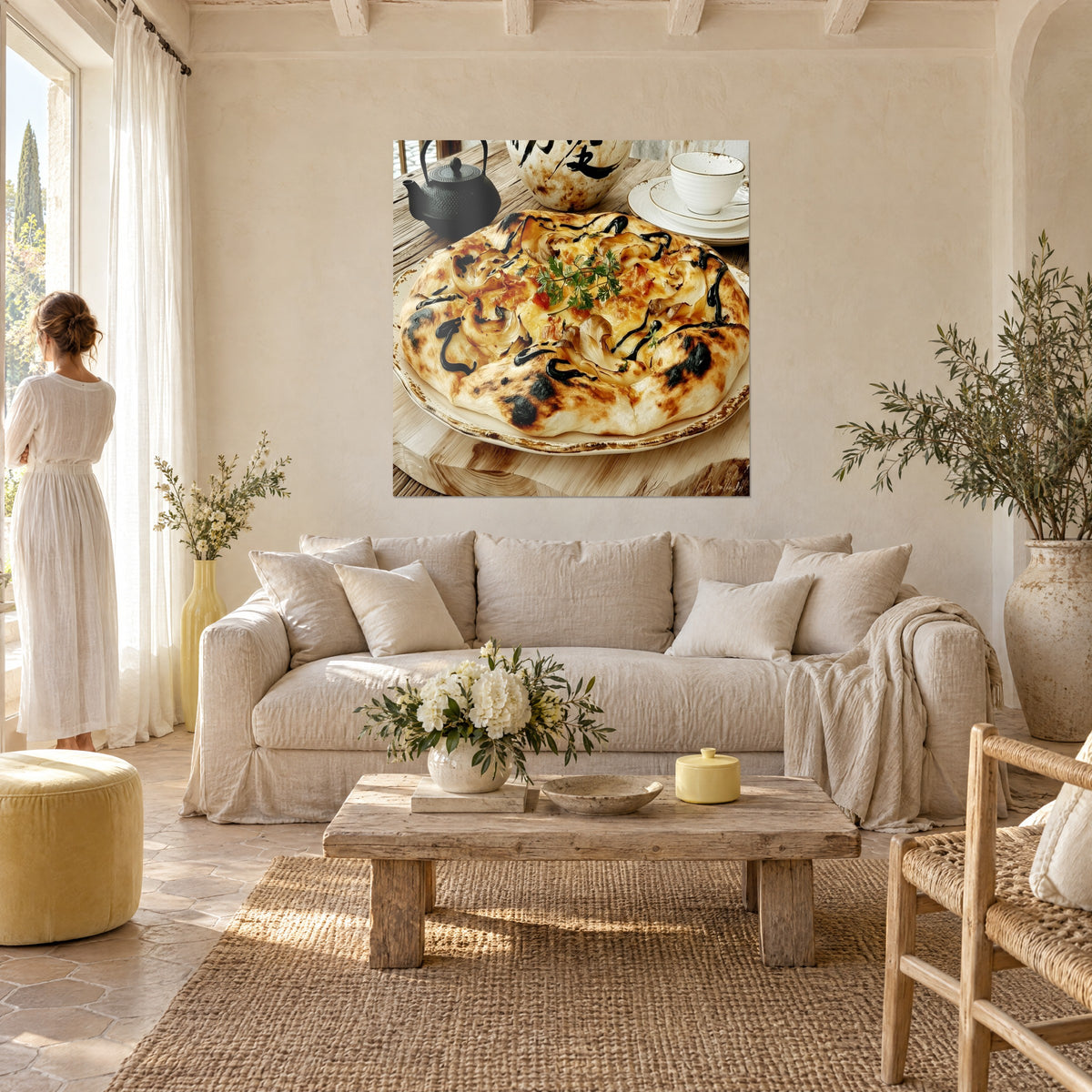 Tableau galette dorée garnie d'oignons fondants, filets noirs et persil, sur un canapé beige, salon lumineux d'un mas