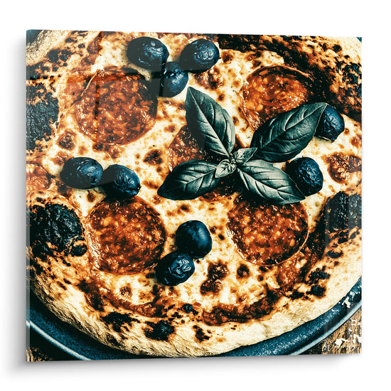 Pizza dorée et anthracite garnie d'olives noires et de basilic vert sombre