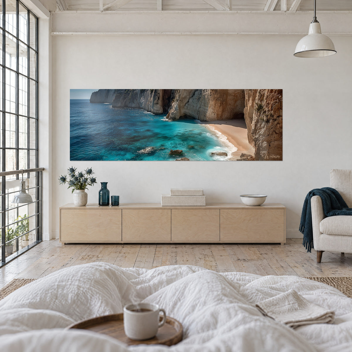 Wall art of a secret beach nestled beneath cream limestone walls, deep blue and turquoise sea, above a bed in a light bedroom