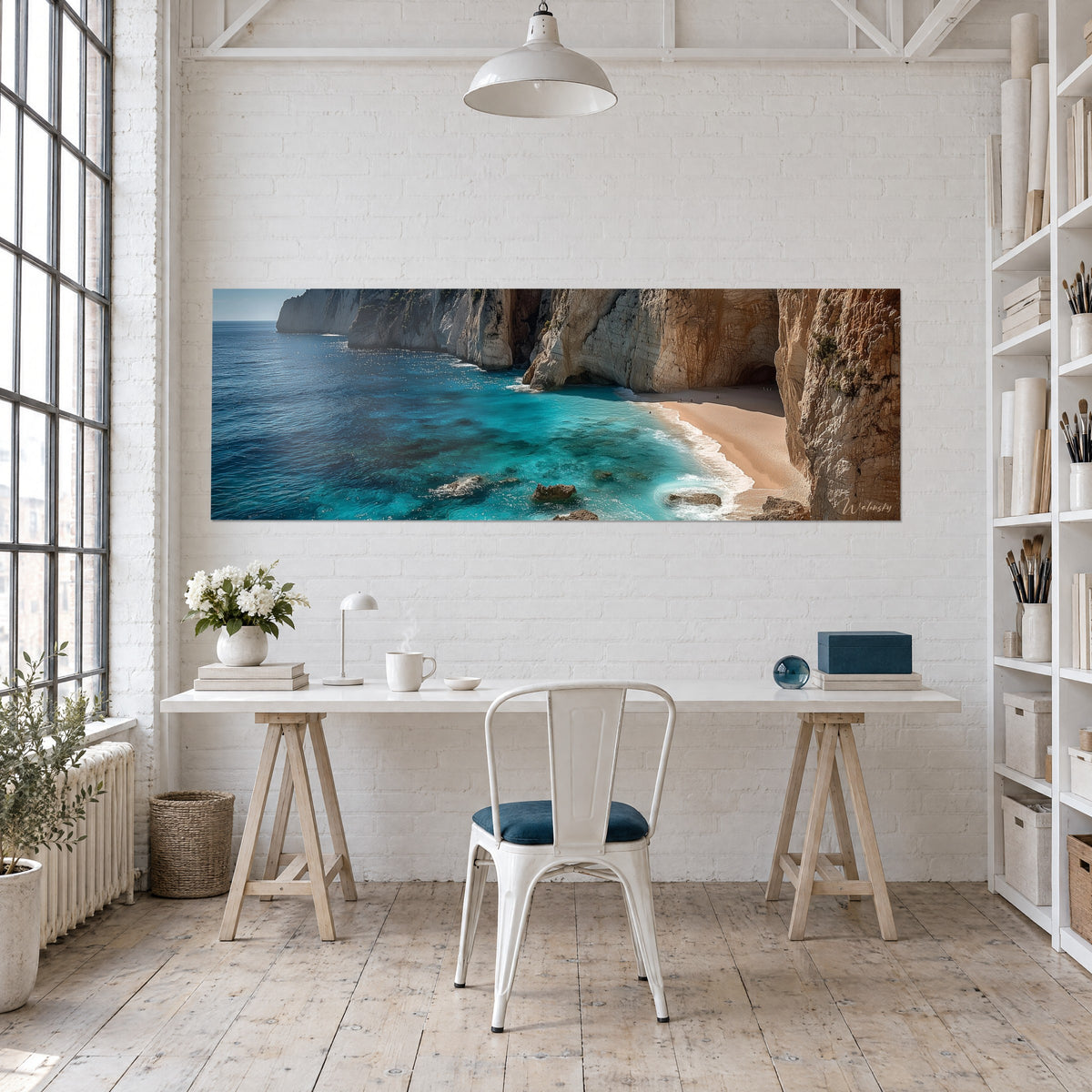 Wall art of a sheltered lagoon between sculpted ochre and grey cliffs, emerald and navy water, hung behind a light wood desk