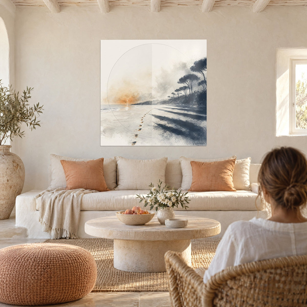 Tableau empreintes de pas vers un soleil orangé, plage grise et pins bleu marine, au-dessus d'un canapé dans un salon lumineux