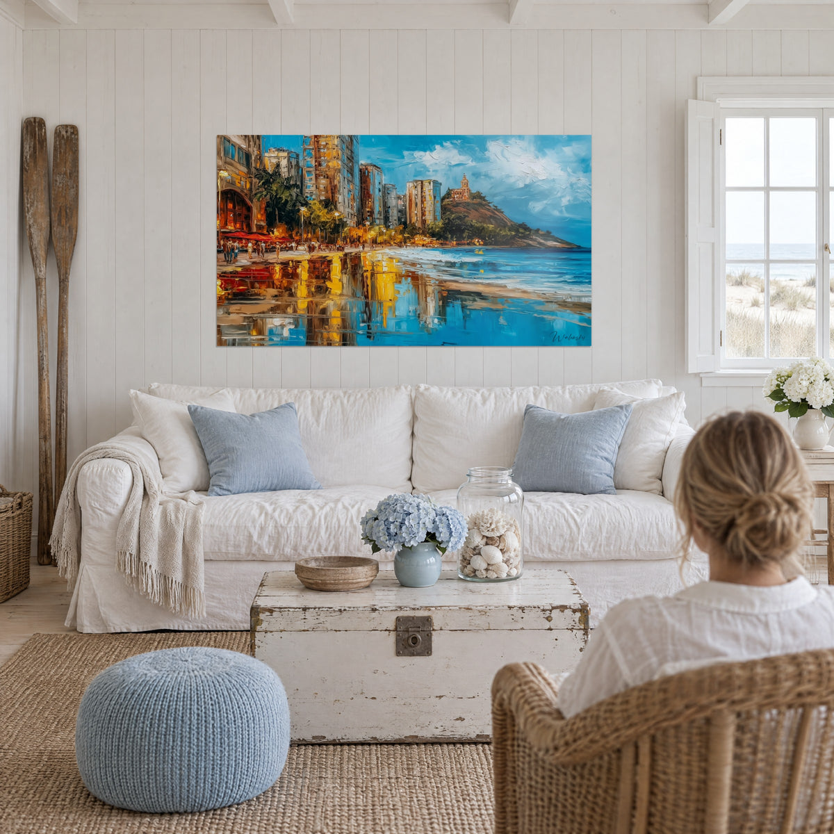 Schilderij gouden zeedijk met okerkleurige torens en amberkleurige weerspiegelingen op het natte zand, boven een bank in een lichte woonkamer
