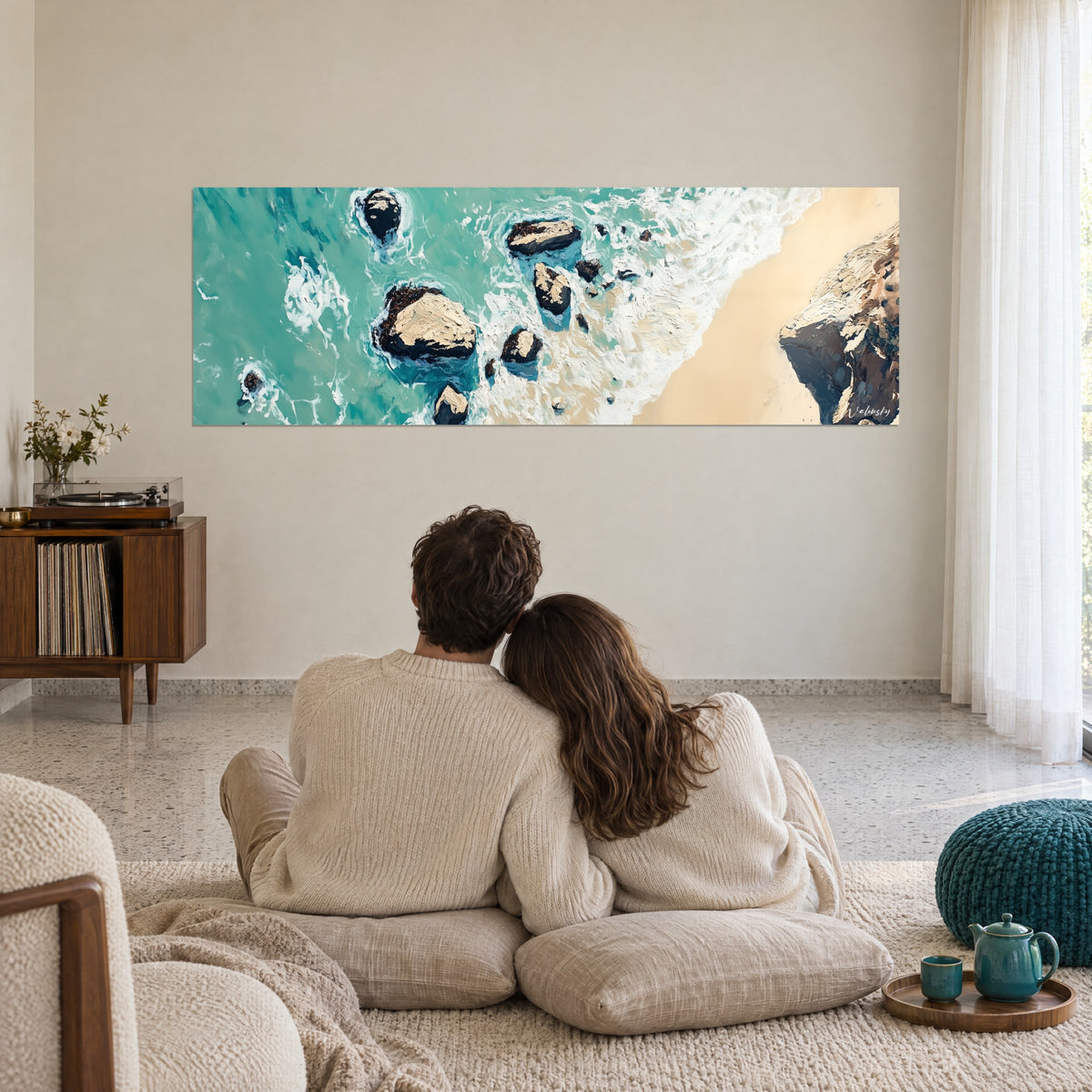 Schilderij rotseilandjes omspoeld door romige golven, okerkleurig zand en turquoise zee, voor een stel dat elkaar omhelst op vloerkussens