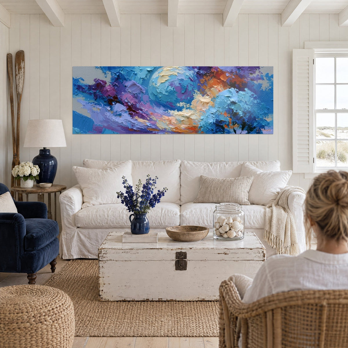 Wall art blue and cream planet with thick paint waves, purple and orange clouds, above a sofa in a bright living room
