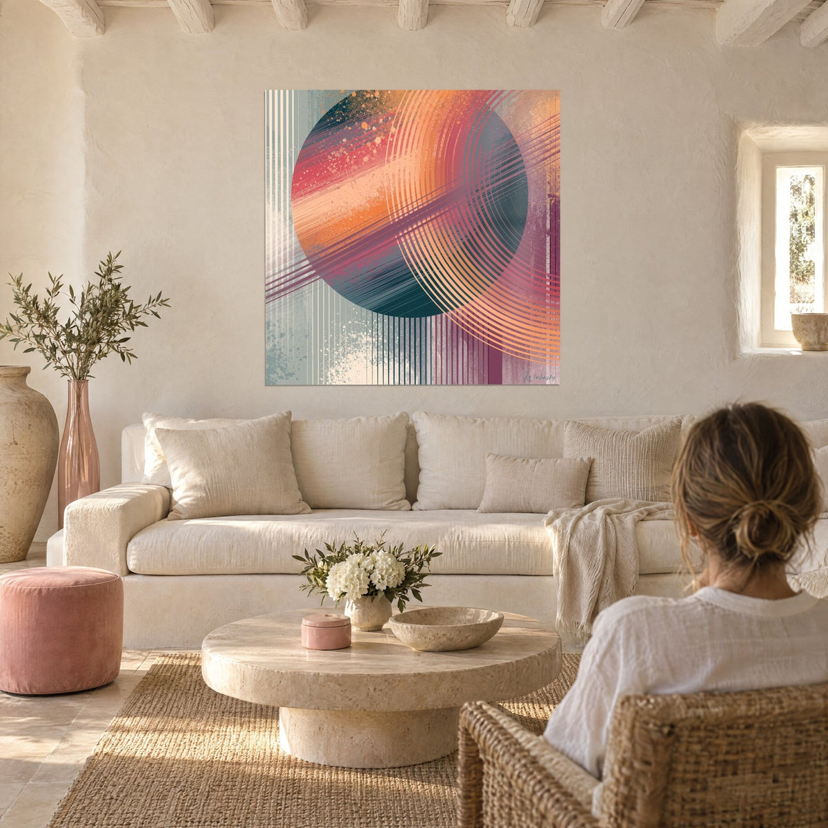 Wall art orange sphere with striped purple orbits, grey-blue background, facing a woman seen from behind, above a sofa in a bright living room