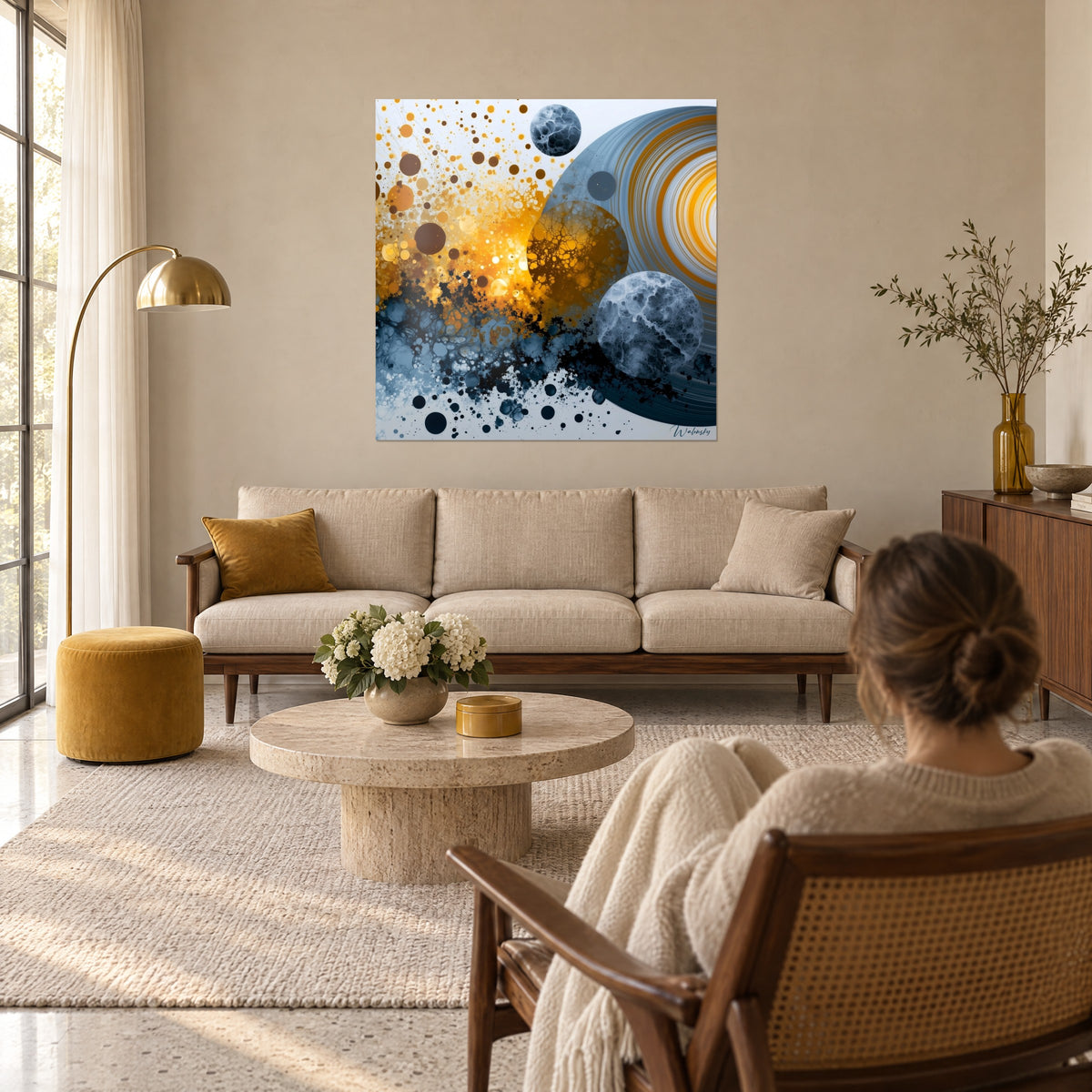 Tableau planètes marbrées éclatées en bulles ocre et bleu ardoise, femme de dos, au-dessus d'un canapé dans un salon lumineux