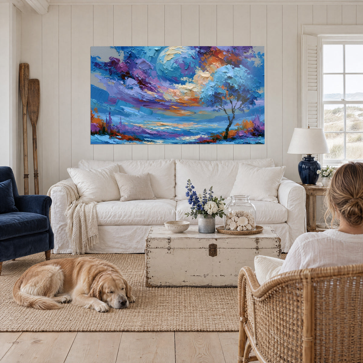 Gemälde blauer Planet mit mauven und ockerfarbenen Streifen, einzelner Baum, liegender Retriever, über einem Sofa in einem hellen Wohnzimmer