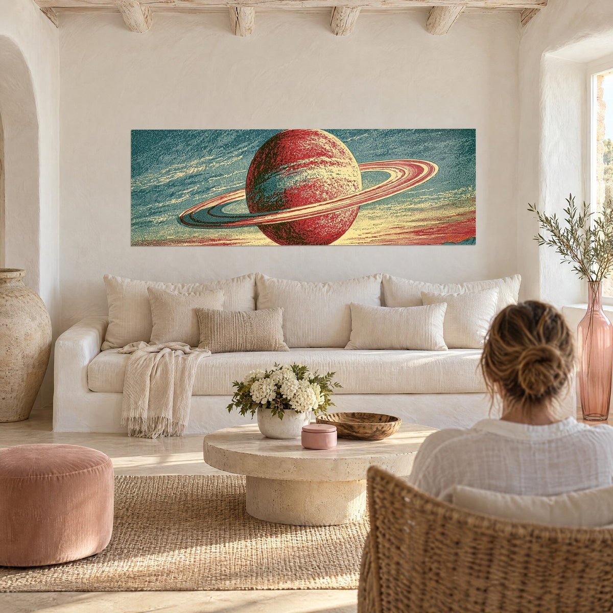 Wall art planet with chalky rings, brick-red sphere against petrol-blue sky, woman seen from behind, above a sofa in a bright living room