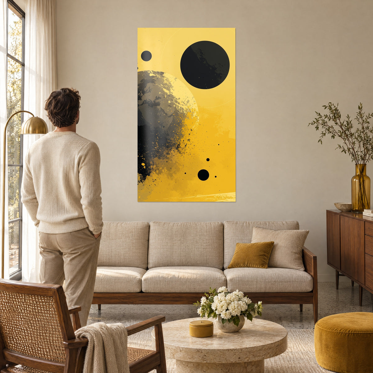 Tableau globe terrestre éclaté gris et jaune, grand disque noir en haut, homme de dos, au-dessus d'un canapé dans un salon lumineux