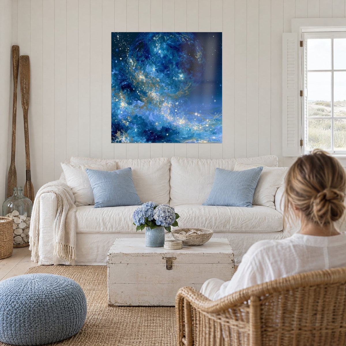 Wall art cobalt blue planet speckled with golden flecks, hung above a sofa in a bright living room