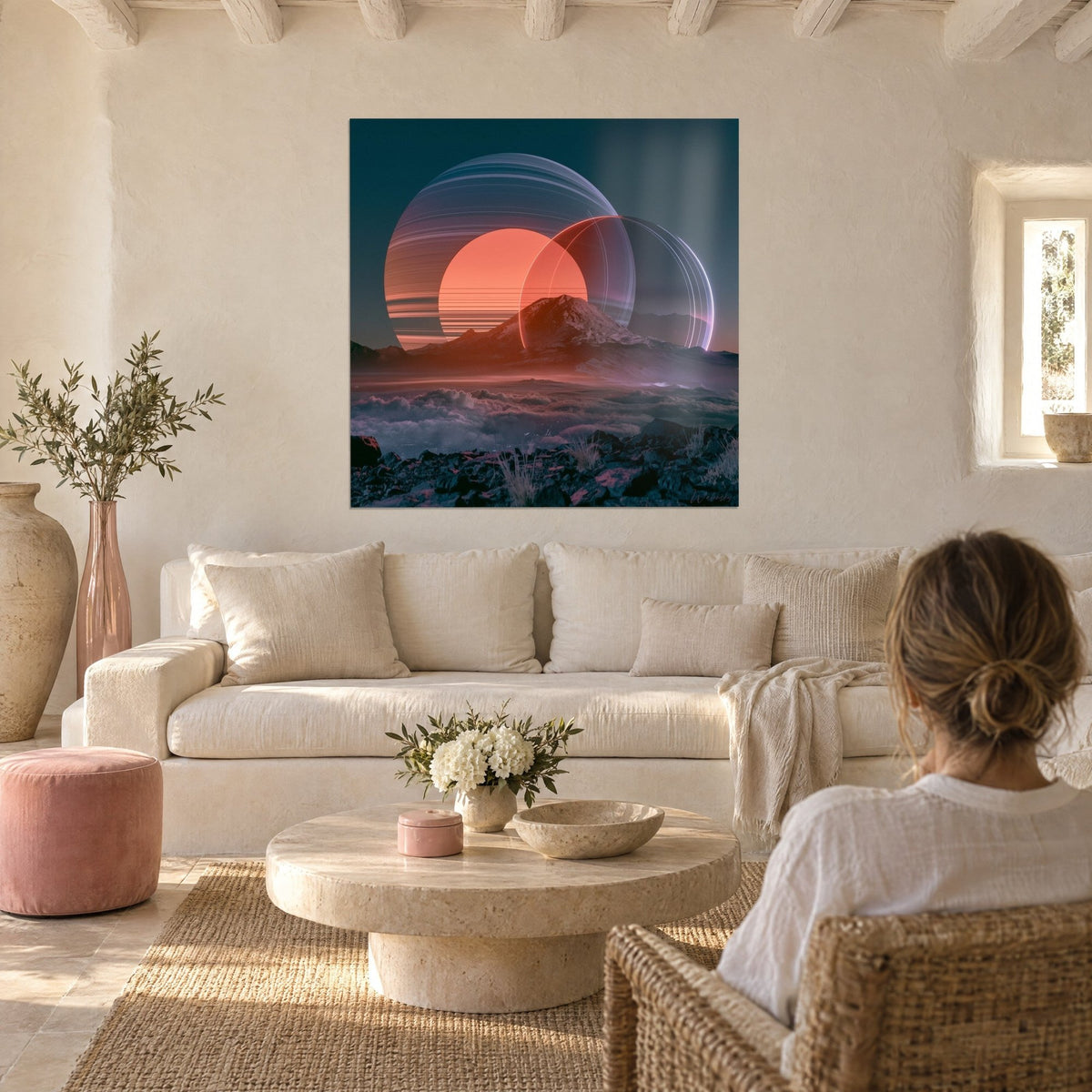 Wall art Saturn-like planet with orange and slate rings over a rocky peak, woman seen from behind, above a sofa in a bright living room