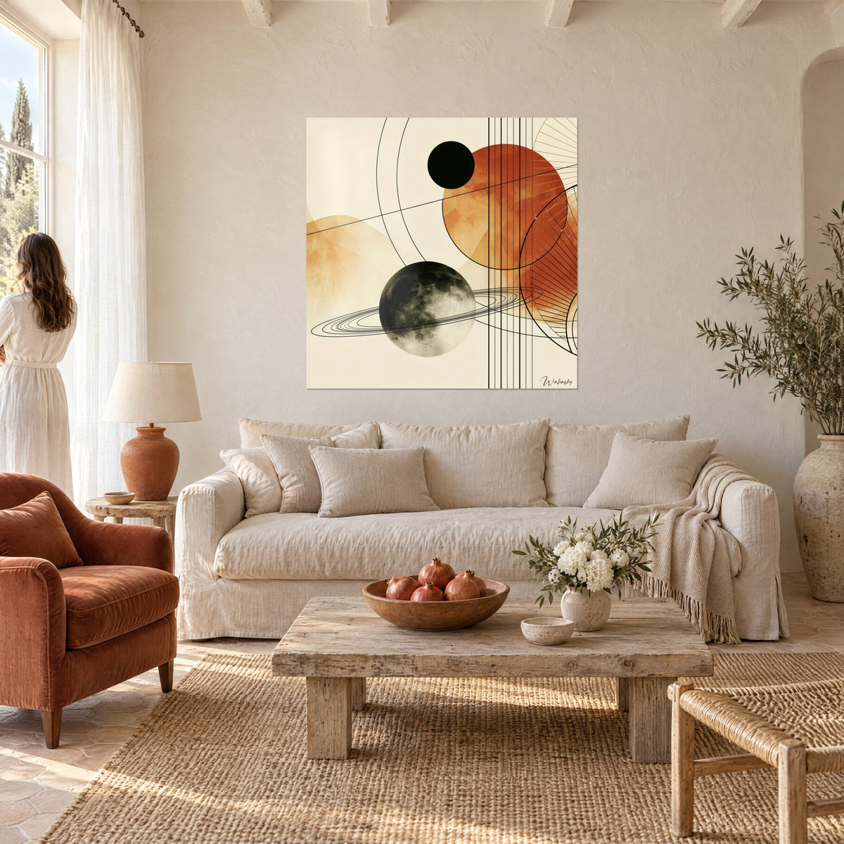 Tableau planète lunaire grise cerclée d'anneaux fins, disque terracotta et soleil noir sur fond crème, au-dessus d'un canapé dans un salon lumineux