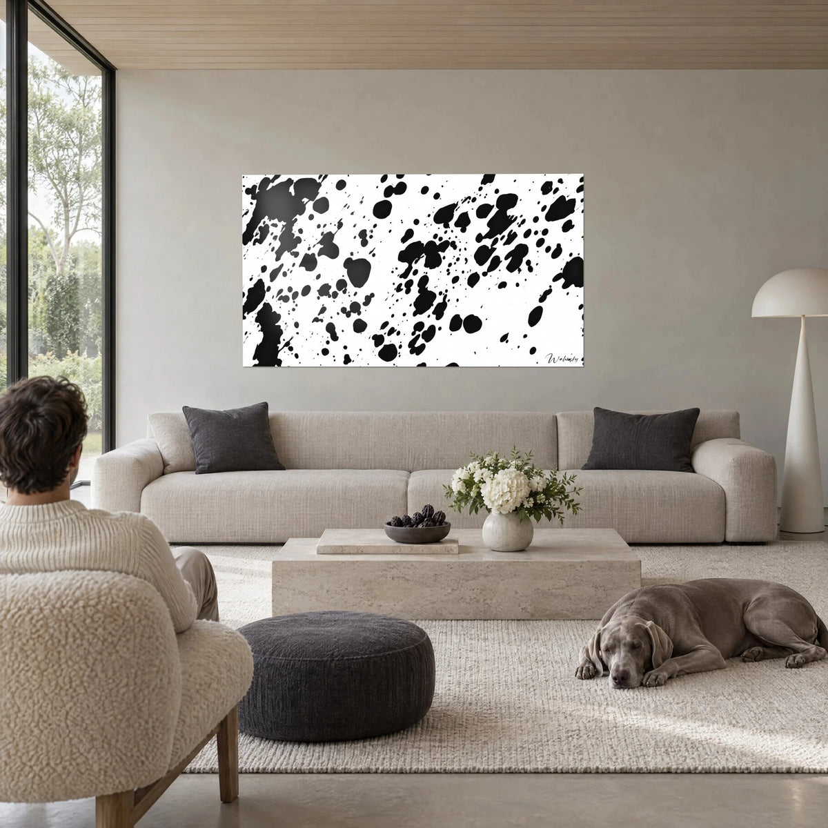 Tableau éclaboussures d'encre noire sur fond blanc, gouttes en pluie, un chien gris au sol au-dessus d'un canapé dans un salon lumineux